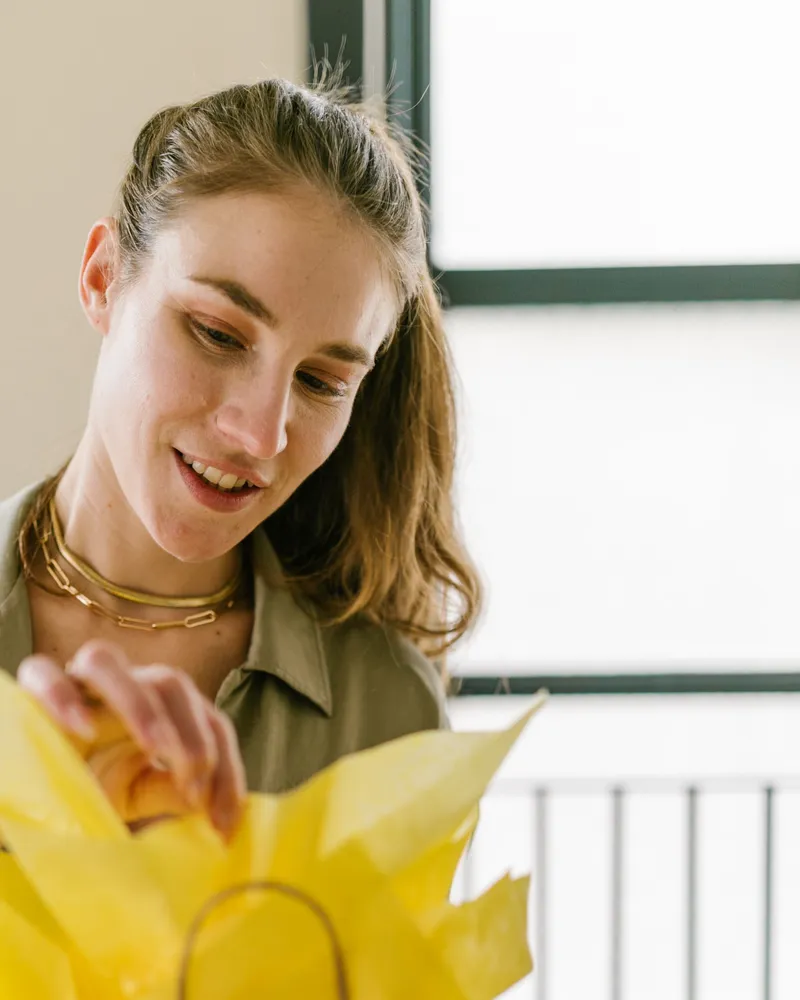 A shop owner packing a gift bag with yellow tissue paper